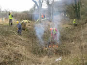 Volunteers get the fire going to burn the smaller material that is chopped down elsewhere. Photo: John Hawkins